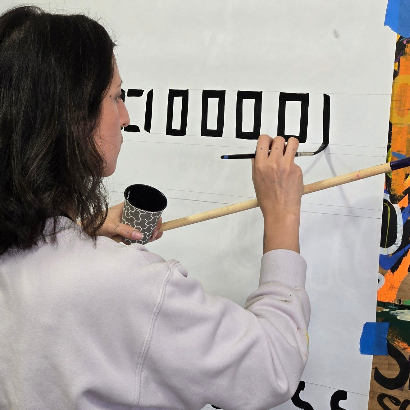 Person holding a mahl stick at a sign painting workshop with john king in Los Angeles